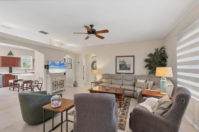 living room featuring a ceiling fan, light tile patterned flooring, visible vents, and arched walkways