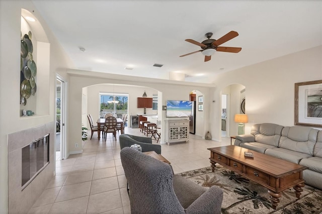 living area with arched walkways, light tile patterned floors, a fireplace, and visible vents