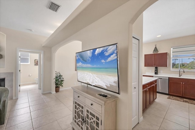 kitchen with visible vents, stainless steel dishwasher, light tile patterned flooring, arched walkways, and a sink