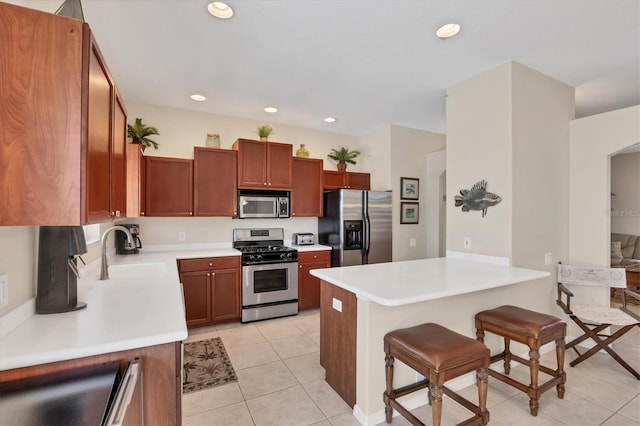 kitchen featuring a sink, appliances with stainless steel finishes, a breakfast bar area, a peninsula, and light tile patterned floors