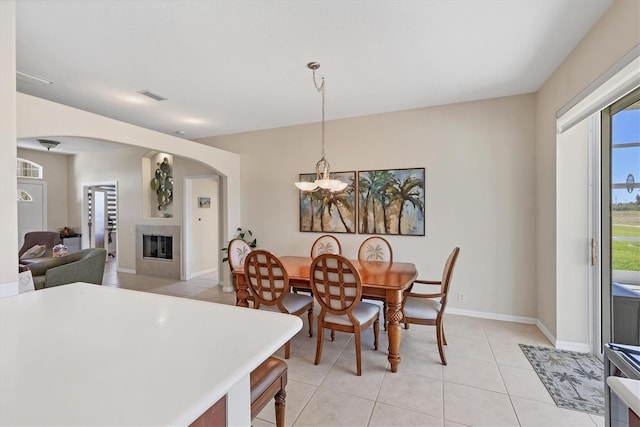 dining area with visible vents, a glass covered fireplace, arched walkways, light tile patterned flooring, and baseboards