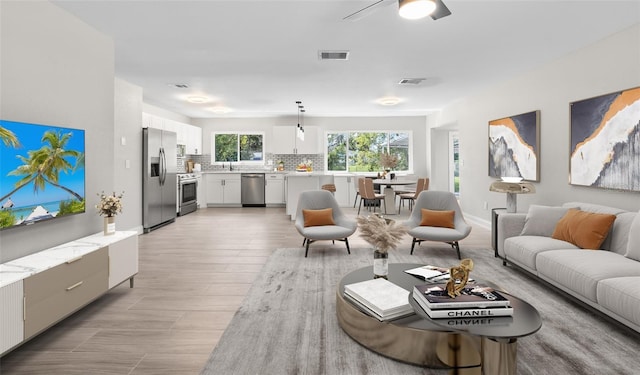 living room with visible vents, light wood-style floors, and a ceiling fan