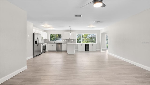 kitchen with backsplash, wine cooler, open floor plan, light countertops, and appliances with stainless steel finishes