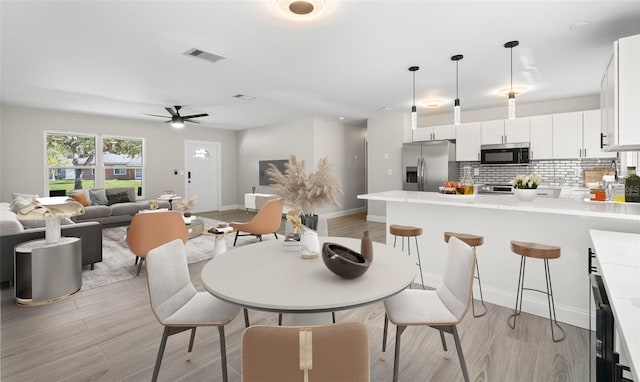 dining space featuring baseboards, visible vents, and light wood-type flooring