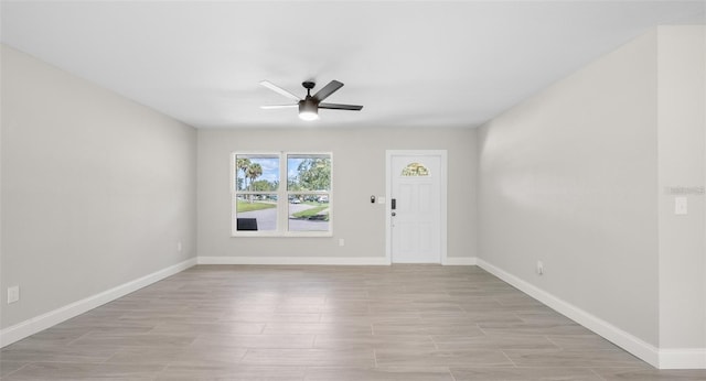 entryway featuring baseboards, a ceiling fan, and light wood finished floors