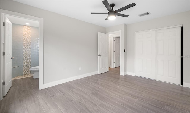 unfurnished bedroom featuring visible vents, baseboards, wood tiled floor, ensuite bathroom, and a closet