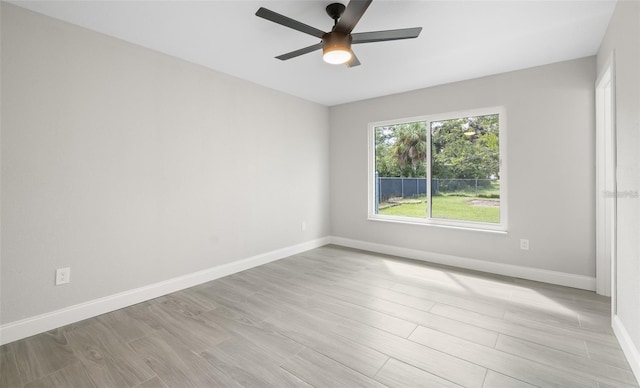 empty room featuring baseboards, light wood-style floors, and ceiling fan