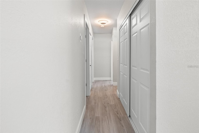 hallway with light wood-style floors and baseboards