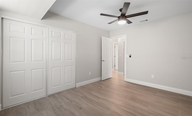 unfurnished bedroom featuring a ceiling fan, baseboards, visible vents, a closet, and light wood-type flooring