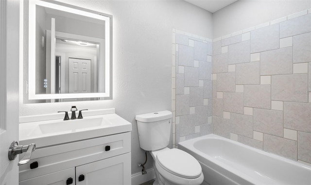 bathroom with toilet, vanity, a textured wall, and washtub / shower combination