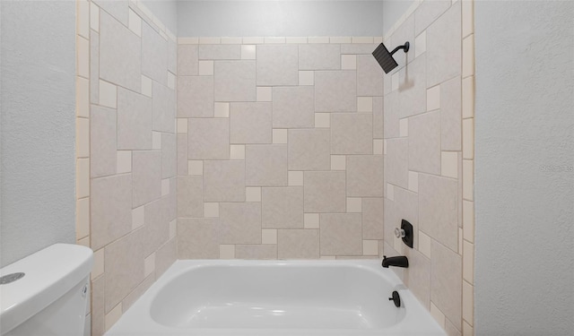 bathroom with shower / tub combination, toilet, and a textured wall