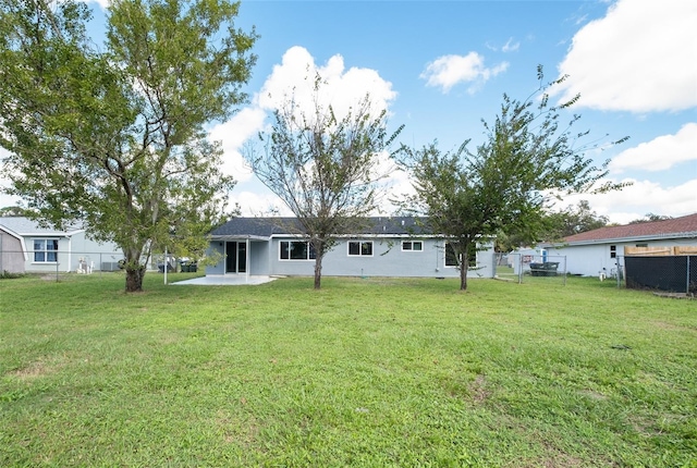 rear view of property featuring fence, a lawn, and a patio area