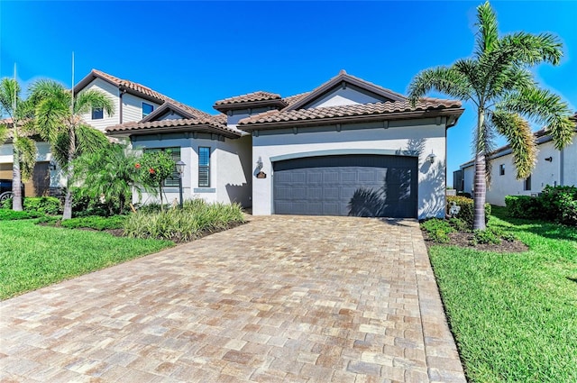 mediterranean / spanish house with stucco siding, an attached garage, decorative driveway, and a front yard