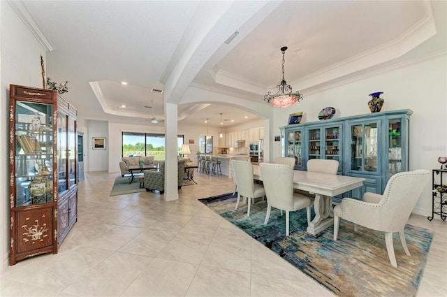 dining space with visible vents, crown molding, a tray ceiling, light tile patterned floors, and arched walkways