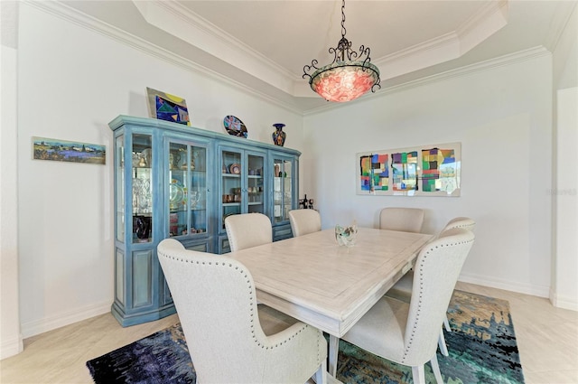 dining area with baseboards, a raised ceiling, light tile patterned flooring, and crown molding