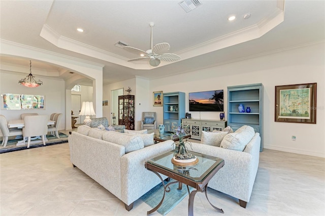 living area featuring visible vents, a raised ceiling, arched walkways, and crown molding