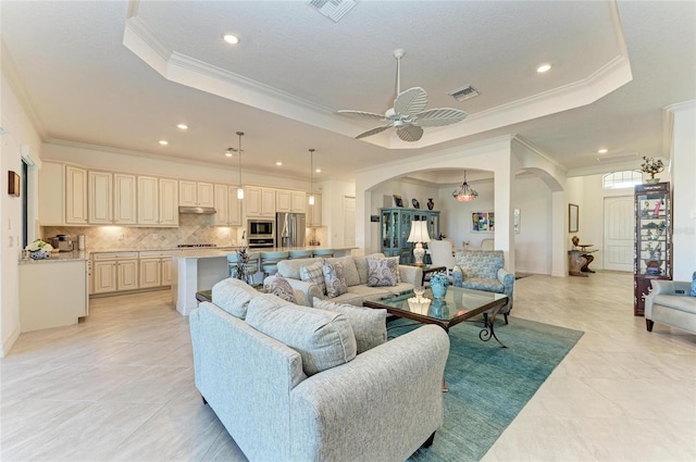 living area featuring arched walkways, visible vents, a raised ceiling, and ornamental molding