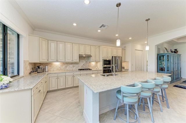 kitchen featuring visible vents, a sink, tasteful backsplash, appliances with stainless steel finishes, and light stone countertops