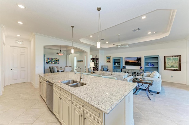 kitchen with visible vents, arched walkways, cream cabinetry, a raised ceiling, and a sink