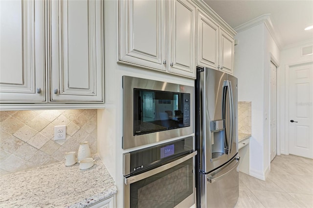 kitchen featuring backsplash, ornamental molding, light tile patterned floors, light stone counters, and appliances with stainless steel finishes