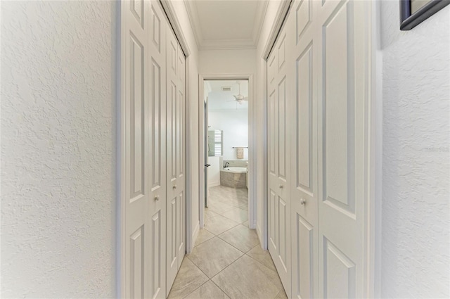 hallway featuring ornamental molding and a textured wall