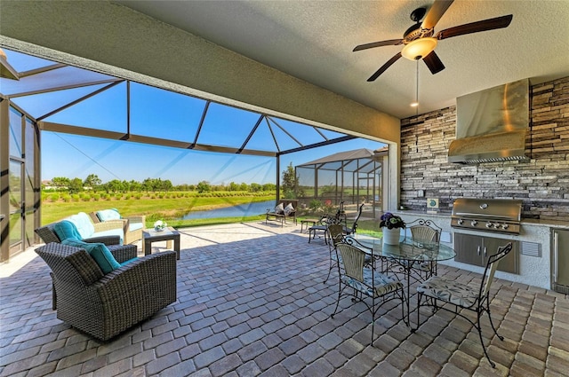 view of patio with a water view, glass enclosure, a grill, exterior kitchen, and outdoor dining area