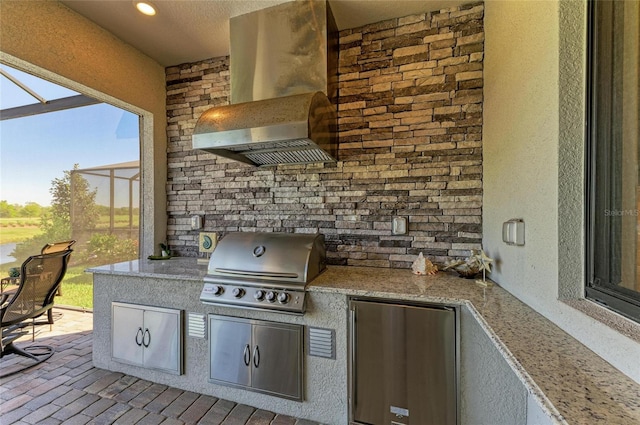 view of patio / terrace featuring glass enclosure, a grill, and an outdoor kitchen