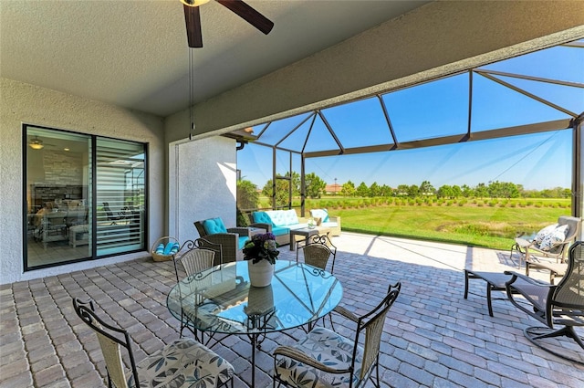 view of patio featuring outdoor lounge area, glass enclosure, and a ceiling fan