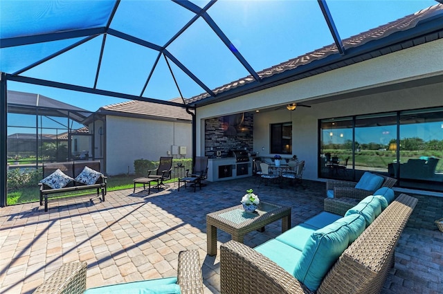 view of patio featuring glass enclosure, a ceiling fan, an outdoor kitchen, outdoor lounge area, and outdoor dry bar