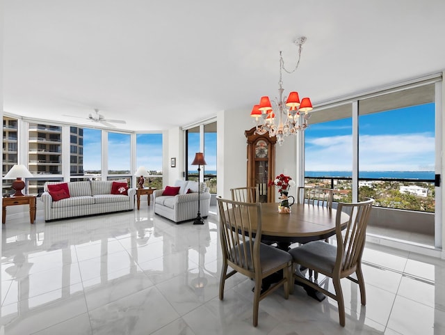 dining space with ceiling fan with notable chandelier, a wall of windows, light tile patterned floors, and a healthy amount of sunlight