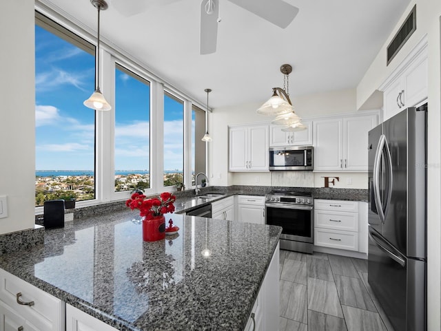 kitchen featuring dark stone countertops, visible vents, a sink, white cabinets, and appliances with stainless steel finishes