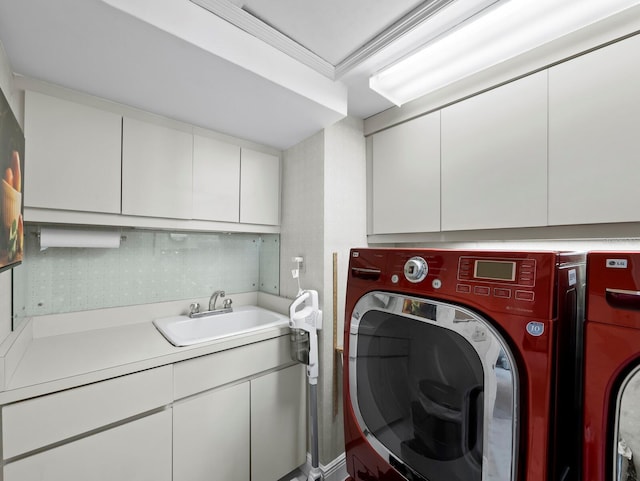 clothes washing area featuring a sink, cabinet space, washing machine and dryer, and ornamental molding