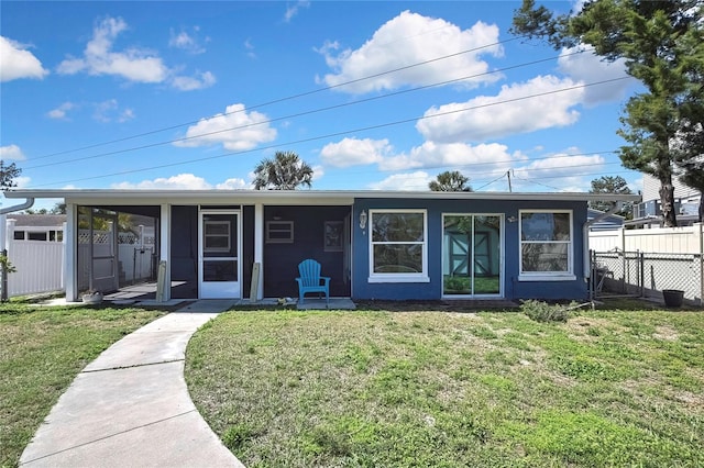 ranch-style house featuring a front lawn, a sunroom, and fence