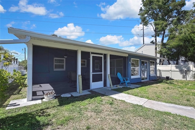 ranch-style home with a sunroom, fence, and a front lawn