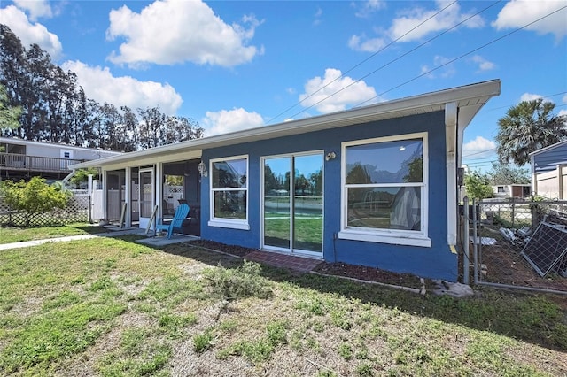 back of property with stucco siding, fence, and a lawn