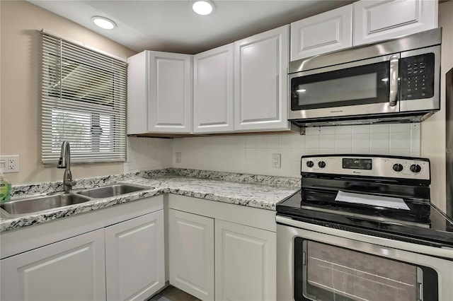 kitchen featuring backsplash, a sink, white cabinetry, stainless steel appliances, and recessed lighting