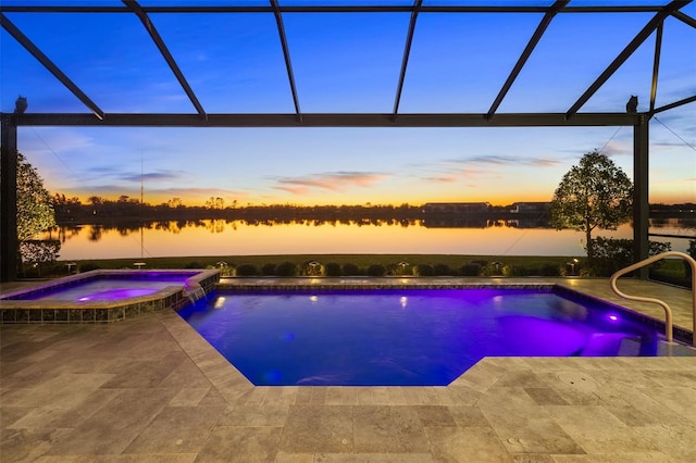 view of pool featuring glass enclosure, a pool with connected hot tub, a patio, and a water view