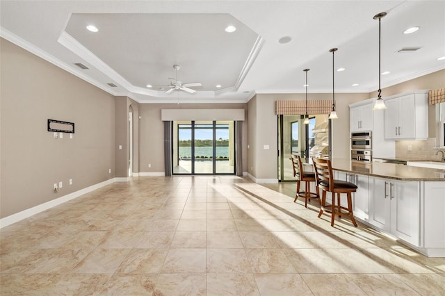 kitchen featuring baseboards, a raised ceiling, crown molding, and white cabinetry