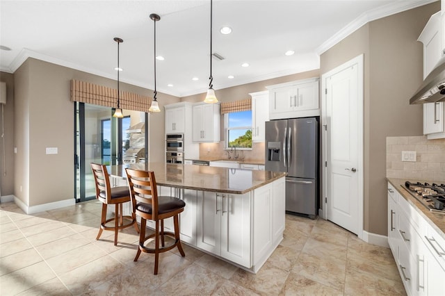 kitchen with a kitchen island, white cabinets, stainless steel appliances, and ornamental molding