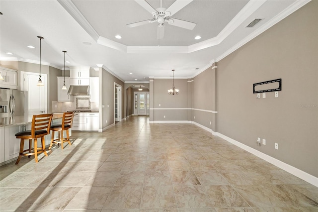 living room featuring a tray ceiling, visible vents, arched walkways, and baseboards