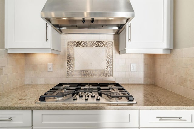 kitchen with tasteful backsplash, white cabinets, ventilation hood, and stainless steel gas stovetop