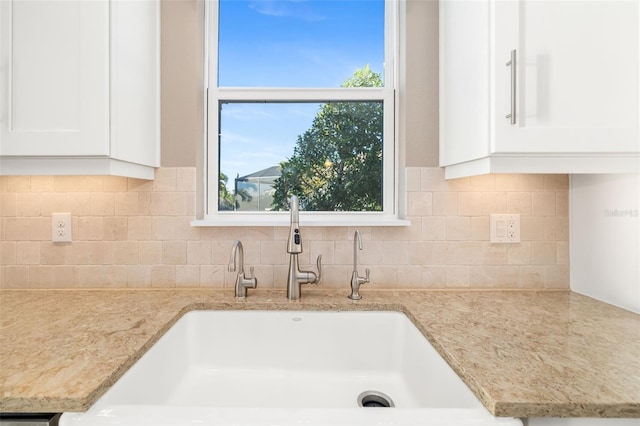 details featuring white cabinetry, light stone countertops, tasteful backsplash, and a sink