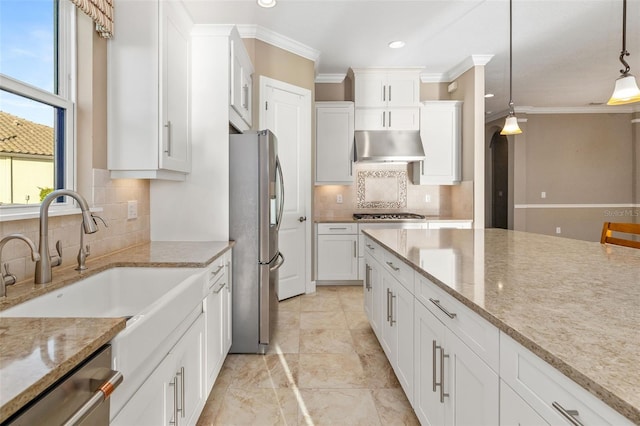 kitchen with under cabinet range hood, ornamental molding, white cabinets, stainless steel appliances, and a sink