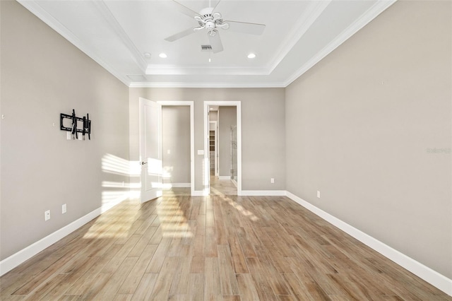 spare room with a raised ceiling, a ceiling fan, baseboards, and light wood finished floors