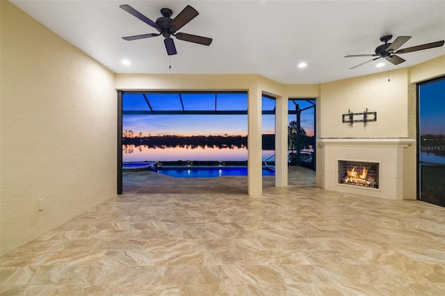 interior space with a textured wall, recessed lighting, a ceiling fan, and a tile fireplace