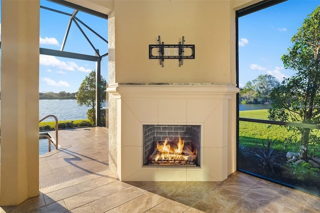 room details with a sunroom, a water view, and a warm lit fireplace