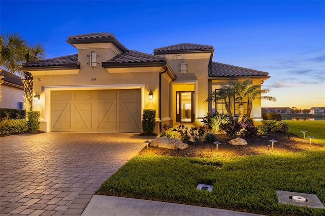 mediterranean / spanish-style home with a tiled roof, stucco siding, and an attached garage