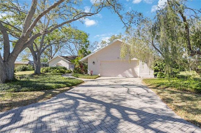 view of side of home with decorative driveway, an attached garage, and stucco siding