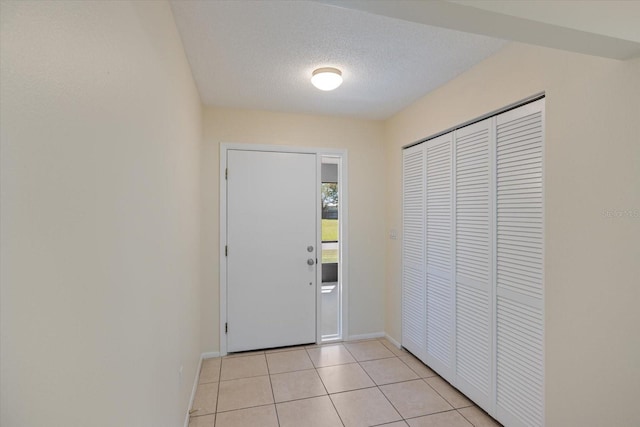 entrance foyer with light tile patterned floors, baseboards, and a textured ceiling