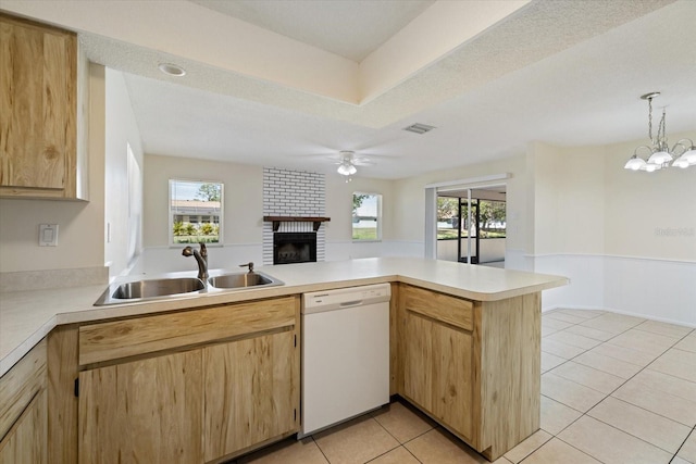 kitchen with a healthy amount of sunlight, a peninsula, white dishwasher, a sink, and light countertops